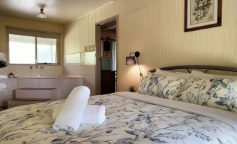 a clean and well - organized bedroom with a king - sized bed , a bathtub , and a bathroom at Kalimna Woods Cottages