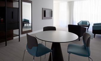 a modern living room with a round table , blue chairs , and a television mounted on the wall at Marriott Maracay Golf Resort