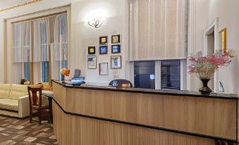 a hotel lobby with a wooden reception desk , two couches , and a vase of flowers at Alexander Hotel