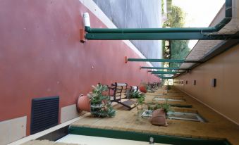 a potted plant is placed on a wooden floor outside of a red wall with metal support beams at Moruya Motel