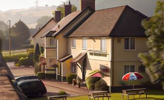 a group of people gathered in front of a large yellow house on a sunny day at The Anchor Inn