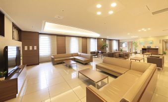 a large , empty hotel lobby with multiple couches and chairs arranged in a seating area at Daiwa Roynet Hotel Hachinohe