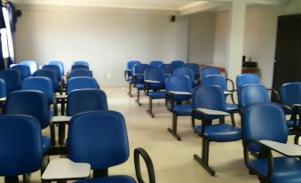 a room with rows of blue chairs and tables , possibly in a classroom setting at Hotel del Sol