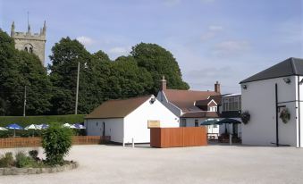 a white house with a brown roof is surrounded by a wooden fence and trees at Thornton Hunt Inn