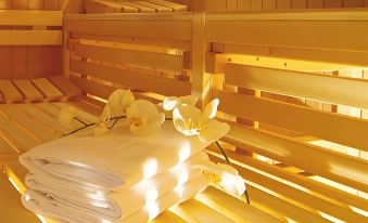 a wooden sauna with two white towels and a yellow flower on top of it at Maritim Hotel Darmstadt
