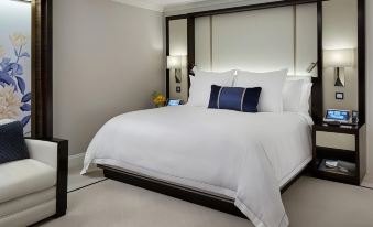 a large , white bed with a black headboard and footboard is in a room with gray walls at Hotel Foret Premier Nampo