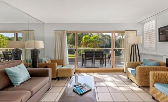 a living room with a couch , coffee table , and sliding glass doors leading to an outdoor patio at Pacific Bay Resort