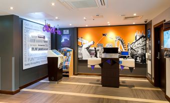 a modern office interior with a reception area , wooden flooring , and a large orange wall mural at Premier Inn Wadebridge