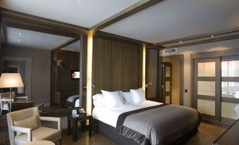 a large bed with white linens and a gray headboard is in the middle of a room at Hotel Val de Neu G.L.