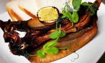 a plate of food with a slice of bread , fish , and greens on a white plate at Blue Bell Hotel