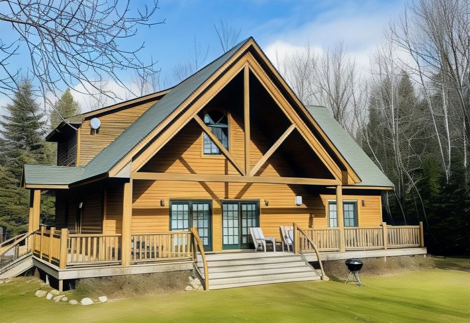 a wooden house with a sloping roof and large windows is situated on a green lawn at Drummond Island Resort & Conference Center
