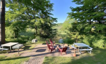 a serene outdoor setting with a wooden deck , dining table , and chairs overlooking a river at Betsie Riverside Resort