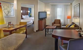 a hotel room with a large flat - screen tv , comfortable seating , and a dining table , all situated in a well - appointed living area at Residence Inn Waldorf