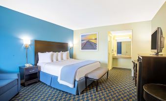 a hotel room with a blue and green color scheme , featuring a king - sized bed , a dresser , and a television at Days Inn by Wyndham Wrightstown McGuire AFB/Bordentown