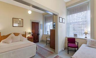 a cozy bedroom with a bed , a chair , and a tv . the room is clean and well - organized at Victoria House