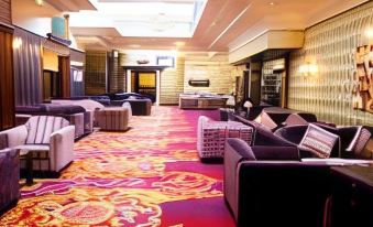 a large , elegant hotel lobby with multiple couches and chairs arranged around a dining table at Hillgrove Hotel, Leisure & Spa