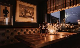 a wooden dining table with two wine glasses and a candle on it , creating a cozy atmosphere at The Ship Inn