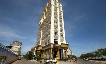 a tall white building with a parking lot in front of it , surrounded by trees at Lbn Asian Hotel