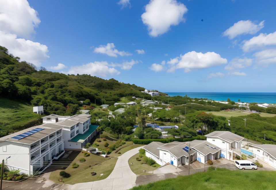 a beautiful resort with multiple buildings , surrounded by lush green trees and a beautiful blue ocean in the background at Siesta Hotel