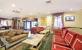 a spacious , well - lit living room with multiple couches and chairs arranged in various positions , creating a cozy atmosphere at Greenwood Hotel