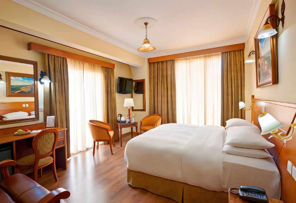 a large bed with white linens is in a room with wooden floors and chairs at Semeli Hotel