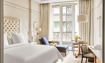 a well - decorated hotel room with a large bed , two chairs , and a window offering a view of the city at Four Seasons Hotel Madrid