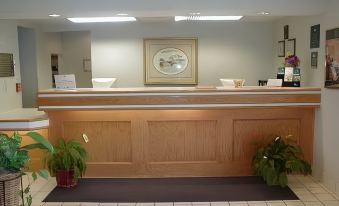 a hotel lobby with a wooden reception desk and potted plants , creating a warm and inviting atmosphere at Homewood Suites by Hilton Columbus - Hilliard