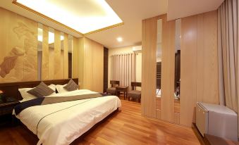a large bed with white linens is in a room with wooden floors and walls at The Home Hotel