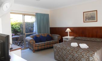 a hotel room with a bed , couch , and sliding glass door leading to a balcony at Augusta's Georgiana Molloy Motel