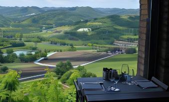 a scenic view of a mountainous area with a table set for dining and glasses on the table at Castello di Gabiano