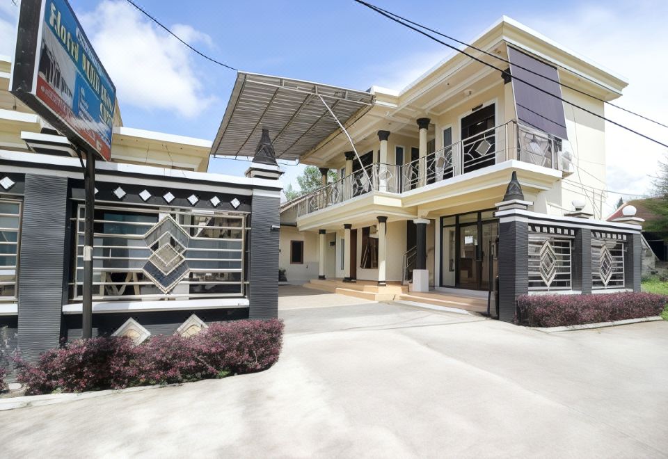 a modern , two - story house with a black and white color scheme , located in a residential area at RedDoorz Syariah @ Jalan Dieng