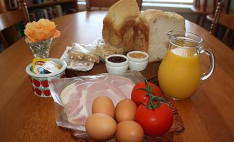 a table is set with a variety of breakfast foods , including eggs , toast , and bacon at Westbury Gingerbread Cottages