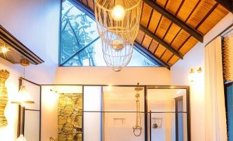 a modern bathroom with a large window , wooden ceiling , and hanging light fixtures , as well as a bathtub and shower area at Kings Camp