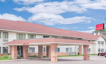 a brick building with a red roof and an archway entrance , under a blue sky with clouds at Ramada by Wyndham Hancock Waterfront