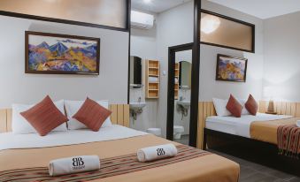 a modern bedroom with two beds , a bathroom , and paintings on the wall , giving it a clean and minimalist feel at Borobudur Bed & Breakfast