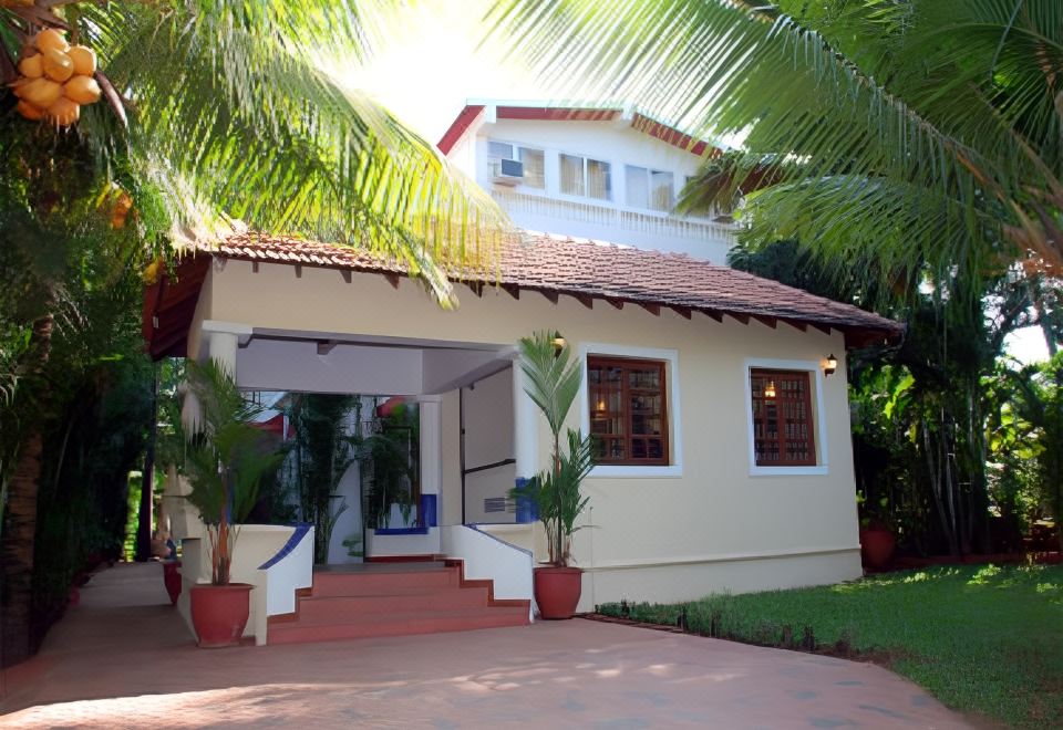 a white building with red tile roof and palm trees in front of it , surrounded by greenery at Casablanca