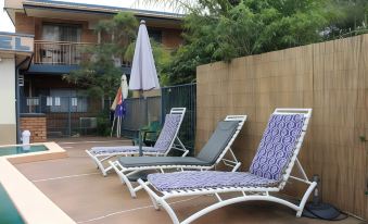 a patio area with several lounge chairs and umbrellas , creating a relaxing atmosphere for guests at Bridge View Motel