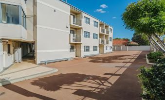 a long , white building with multiple balconies and a parking lot in front of it at Canning Bridge Auto Lodge