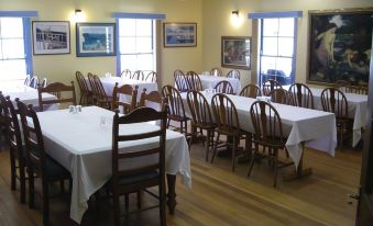 a dining room with several tables and chairs , all covered with white tablecloths , is set up for a meal at Bestbrook Mountain Farmstay