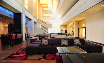 a spacious , well - lit lobby with multiple couches , chairs , and tables arranged for guests to relax at Mobile Marriott