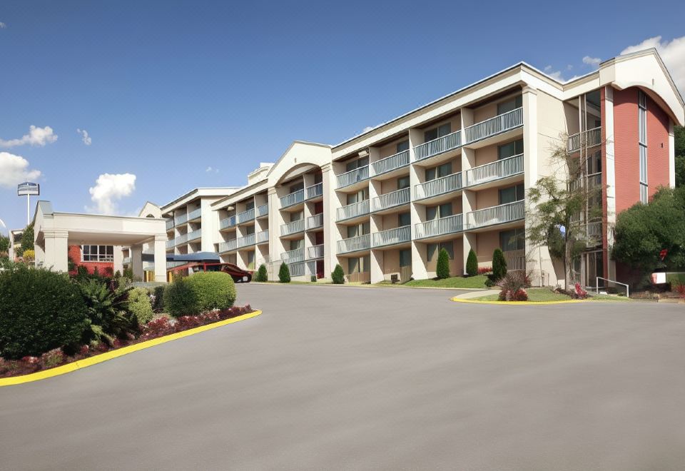 a large hotel with multiple levels of balconies , surrounded by trees and other buildings , under a clear blue sky at Wyndham Garden Washington DC Area