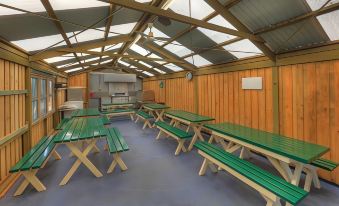 a room with green benches and wooden tables , set up for a meal or dining experience at Hi-Way Motel Grafton - Contactless