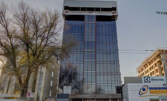 a tall , modern building with a glass facade is situated in a city street , surrounded by trees at Hotel Lulu