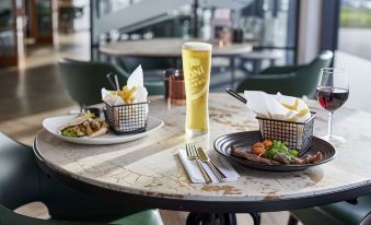 a table with plates , silverware , and a glass of beer is set up in a restaurant at Hampton by Hilton Humberside Airport