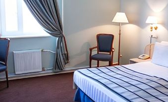 a hotel room with a blue and white striped bed , two chairs , and a window at Petro Sport Hotel