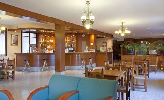 a spacious room with wooden furniture , including a couch , chairs , and tables , as well as a bar area at Hotel Mora