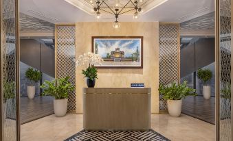a hotel lobby with a large painting on the wall , two potted plants , and a check - in desk at Melia Vinpearl Hue