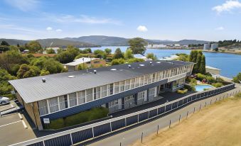 aerial view of a large building surrounded by a fence , with a lake in the background at Waterfront Lodge Motel