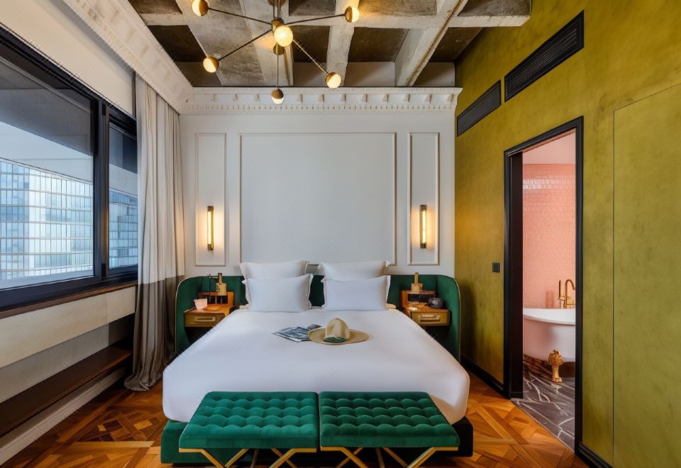 The bedroom features a large bed and a green accent wall in the middle, as well as an open space at Brown BoBo, a Member of Brown Hotels