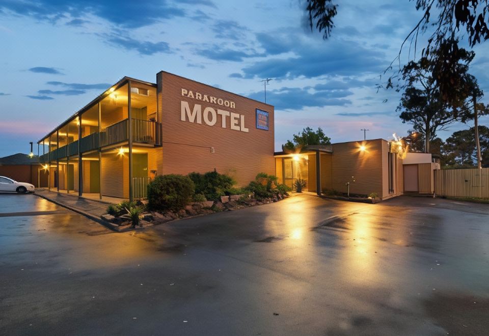 "a hotel building with the name "" pendleton motel "" lit up at night , surrounded by trees and parked cars" at Parkwood Motel & Apartments